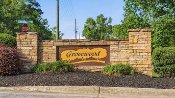 A stone wall with a sign that reads 'Grovewood' and street signs for 'Barber Mill' and 'Grovewood.'