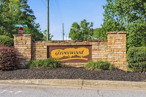 Eine Steinmauer mit einem Schild, auf dem 'Grovewood' steht, und Straßenschildern für 'Barber Mill' und 'Grovewood'.