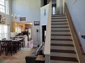 Un grand espace de vie comprenant un escalier, un coin repas et une cuisine.