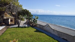 Une vue sur la côte, avec une zone herbeuse, un mur en béton et un bâtiment doté d’une fenêtre.