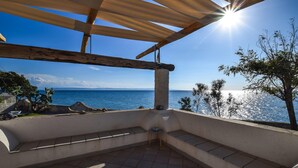 Un espace extérieur abrité, aménagé pour s’asseoir, avec vue sur la mer.