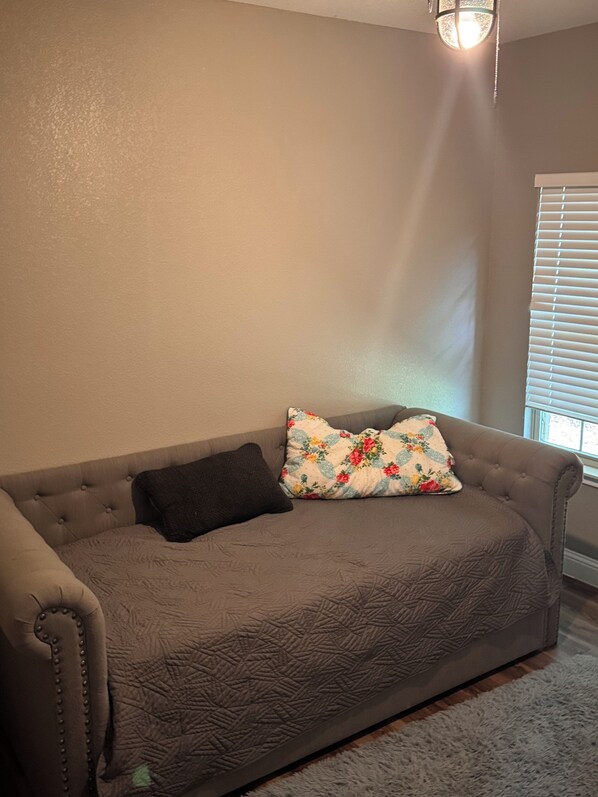 A living room with a grey sofa, a floral pillow, and a dark throw pillow. - Charming 3-bedroom house with AC in Quinlan (Quinlan)
