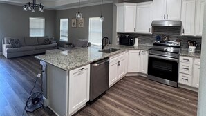 Una cocina moderna con gabinetes blancos, encimeras de granito y electrodomésticos de acero inoxidable.