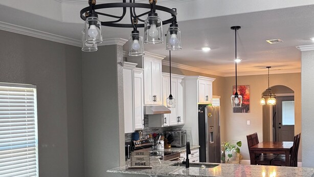 Una cocina moderna con una isla central, taburetes de bar e iluminación colgante.