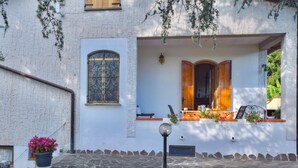 Un edificio con entrada empedrada de piedra, ventana con rejas de hierro decorativas y puerta de madera.