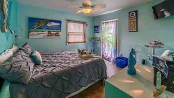 A bedroom with a bed, a ceiling fan, a TV, and a window with blinds.