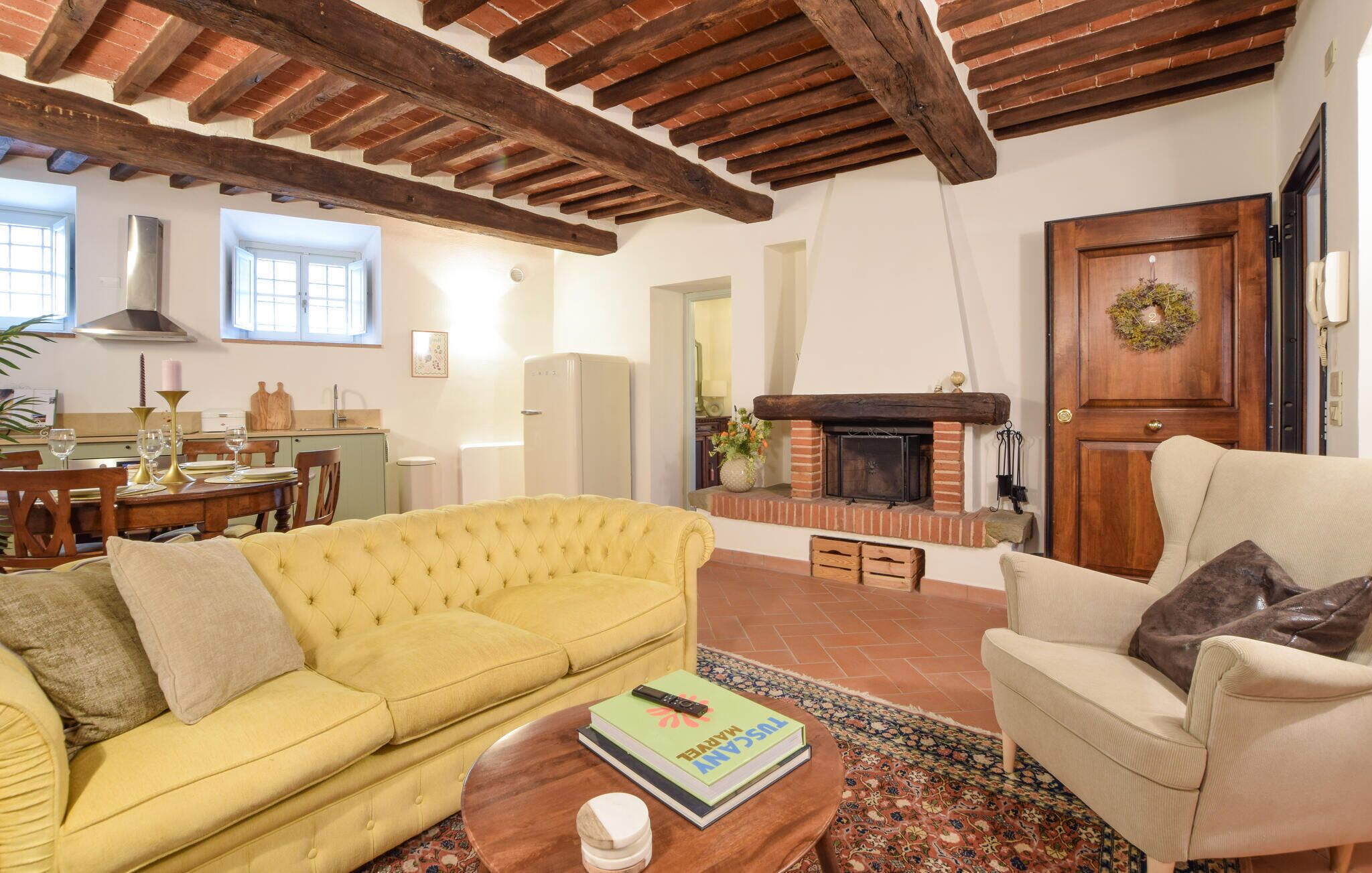 Un soggiorno accogliente con un divano giallo, una poltrona beige e un caminetto.