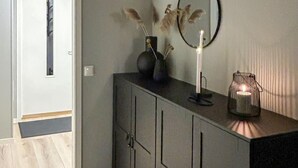 A modern interior with a grey cabinet, a mirror, and two lit candles on a table.