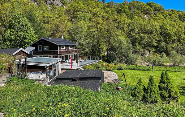 Una casa moderna con un'ampia terrazza, immersa nel verde e con le montagne sullo sfondo.