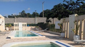 A pool area with two rectangular pools, lounge chairs, and a stone wall. - Charming 2-bedroom bungalow in Kilifi County with AC (Kilifi County)