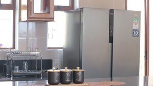 A kitchen with a stainless steel refrigerator, a coffee machine, and three dark-colored jars on the counter. - Charming 2-bedroom bungalow in Kilifi County with AC (Kilifi County)