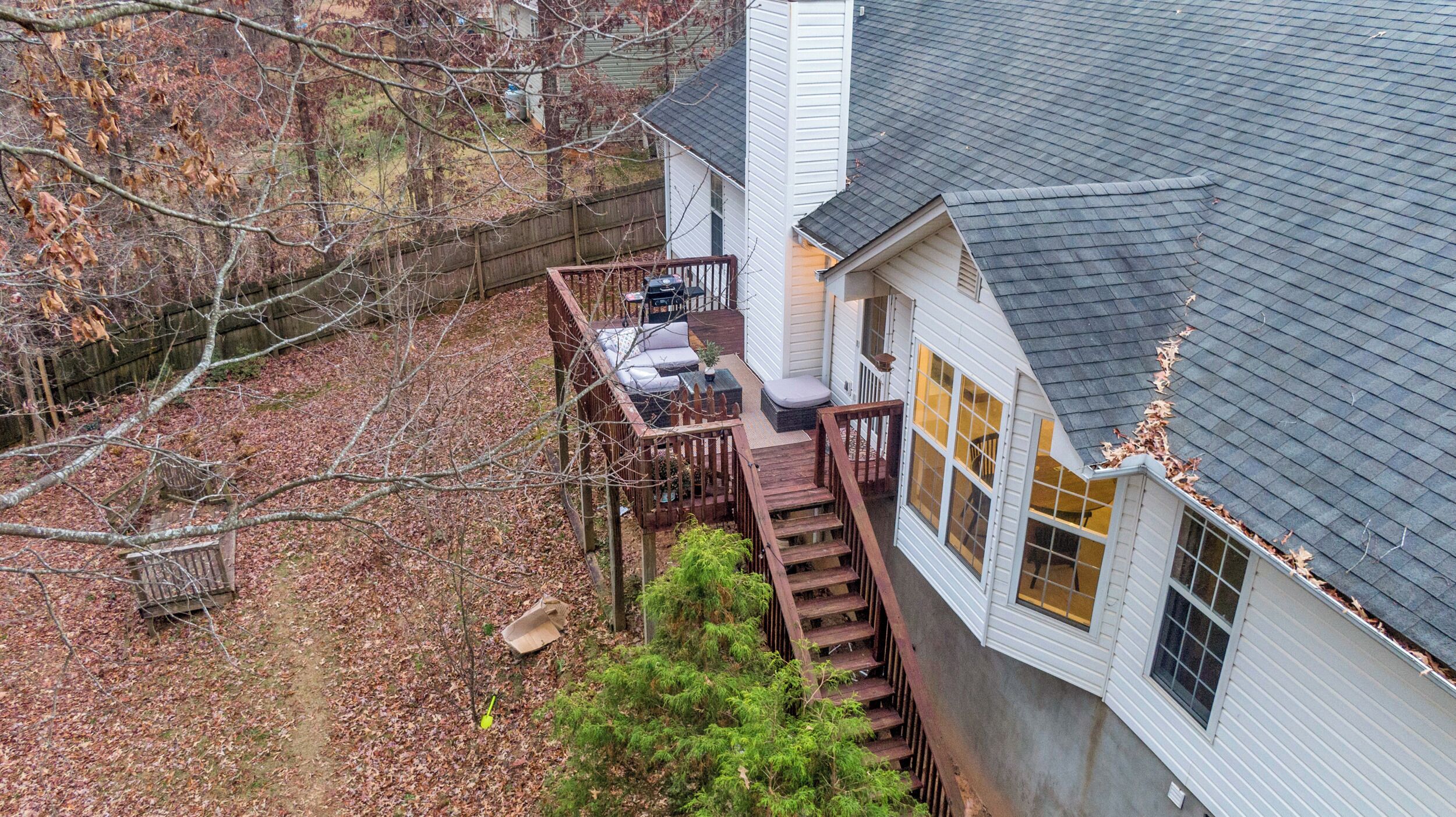A house with a deck, a staircase leading to the front door, and a fenced yard.