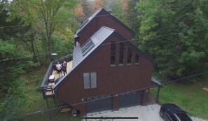 Une maison à deux étages avec un balcon, entourée d’arbres.