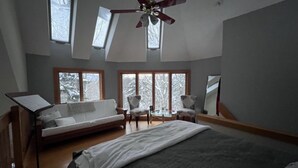 A bedroom with a bed, a ceiling fan, a piano, and large windows. - THE BIJOU -  a Precious Gem in the Green Mountains. HOT TUB, PET OK, HANDICAP (Rochester)