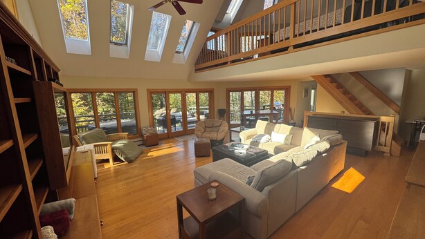A spacious living room with a high ceiling, large windows, and a wooden staircase. - THE BIJOU -  a Precious Gem in the Green Mountains. HOT TUB, PET OK, HANDICAP (Rochester)