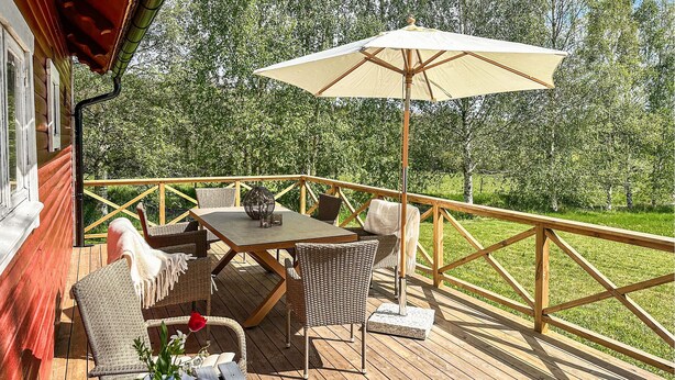 Une terrasse en bois avec des meubles d’extérieur, une table et un parasol.