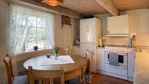 Une cuisine chaleureuse avec une table et des chaises en bois, un réfrigérateur blanc et une cuisinière.