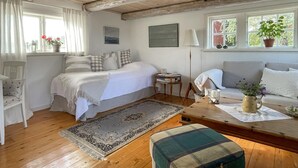 Une chambre confortable avec un lit, une table de chevet, une lampe et une vue sur l’extérieur par une fenêtre.