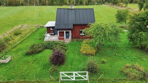 A single-story house with a dark roof, surrounded by a well-maintained lawn and a few trees. - Lovely home in Furudal with sauna (Furudal)