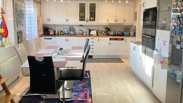 A modern kitchen with white cabinets, a dining area with a table and chairs, and a refrigerator with magnets. - Apartment in S West Sthlm close to Metro (Hägersten)