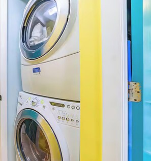 A laundry area with two stacked washing machines, a basket, and a ceiling fan.