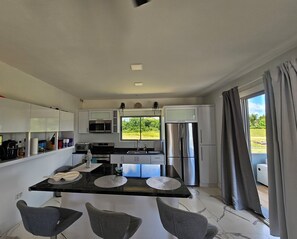 Cocina moderna con una isla central, electrodomésticos de acero inoxidable y vistas a zonas verdes.