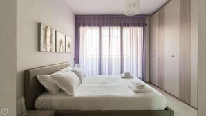 A bedroom with a bed, pillows, a bedside table, a wardrobe, and a window with curtains. - Italianway - Marcantonio (Milan)