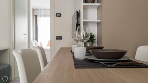 A dining table with white chairs, a wine glass, a bowl, and a small potted plant. - Italianway - Marcantonio (Milan)