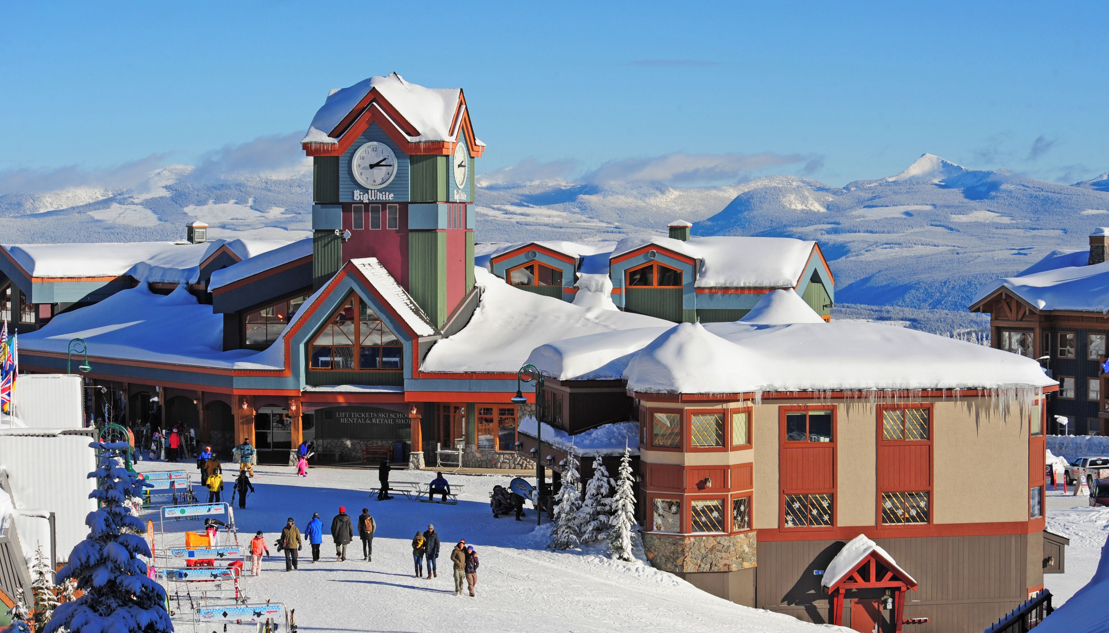 A ski resort with a prominent clock tower, a lift ticket shop, and snow-covered buildings.