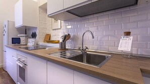 A modern kitchen with a stainless steel sink, wooden countertop, and white subway tiles backsplash. - Italianway Corso Lodi 121 (Milan)