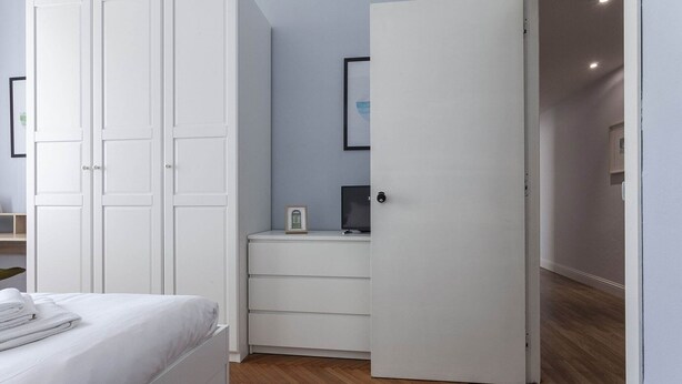 A bedroom with a bed, a wardrobe, a desk with a computer, and a door leading to another room. - Italianway Corso Lodi 121 (Milan)