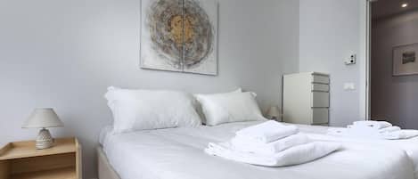 Una habitación de hotel con una cama, una mesita de noche, una lámpara, un cuadro y un armario.