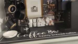 A kitchen counter with a coffee station, a framed picture, and a decorative wall with floral and mushroom patterns.