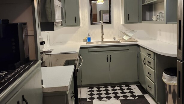 A kitchen with a checkered floor, a ceiling fan, and a sink.