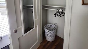 A walk-in closet with white shelves, a white laundry basket, and a door with a white frame.