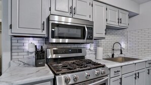 A modern kitchen with stainless steel appliances, white cabinetry, and a marble countertop. - Gowen 2411 - 3BR Mid-Term Stay, All Utilities Incl (Wausau)