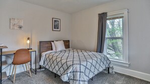 A bedroom with a bed, a desk, a chair, a window with curtains, and two wall-mounted pictures. - Gowen 2411 - 3BR Mid-Term Stay, All Utilities Incl (Wausau)