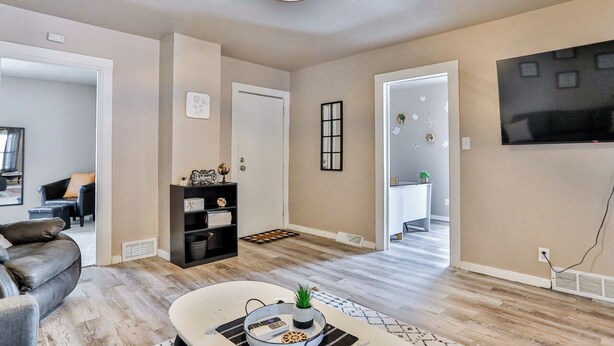 A modern living room with a ceiling fan, a flat-screen TV mounted on the wall, and a dining area with a table and chairs. - Gowen 2415 - 2BR Mid-Term Stay, All Utilities Incl (Wausau)