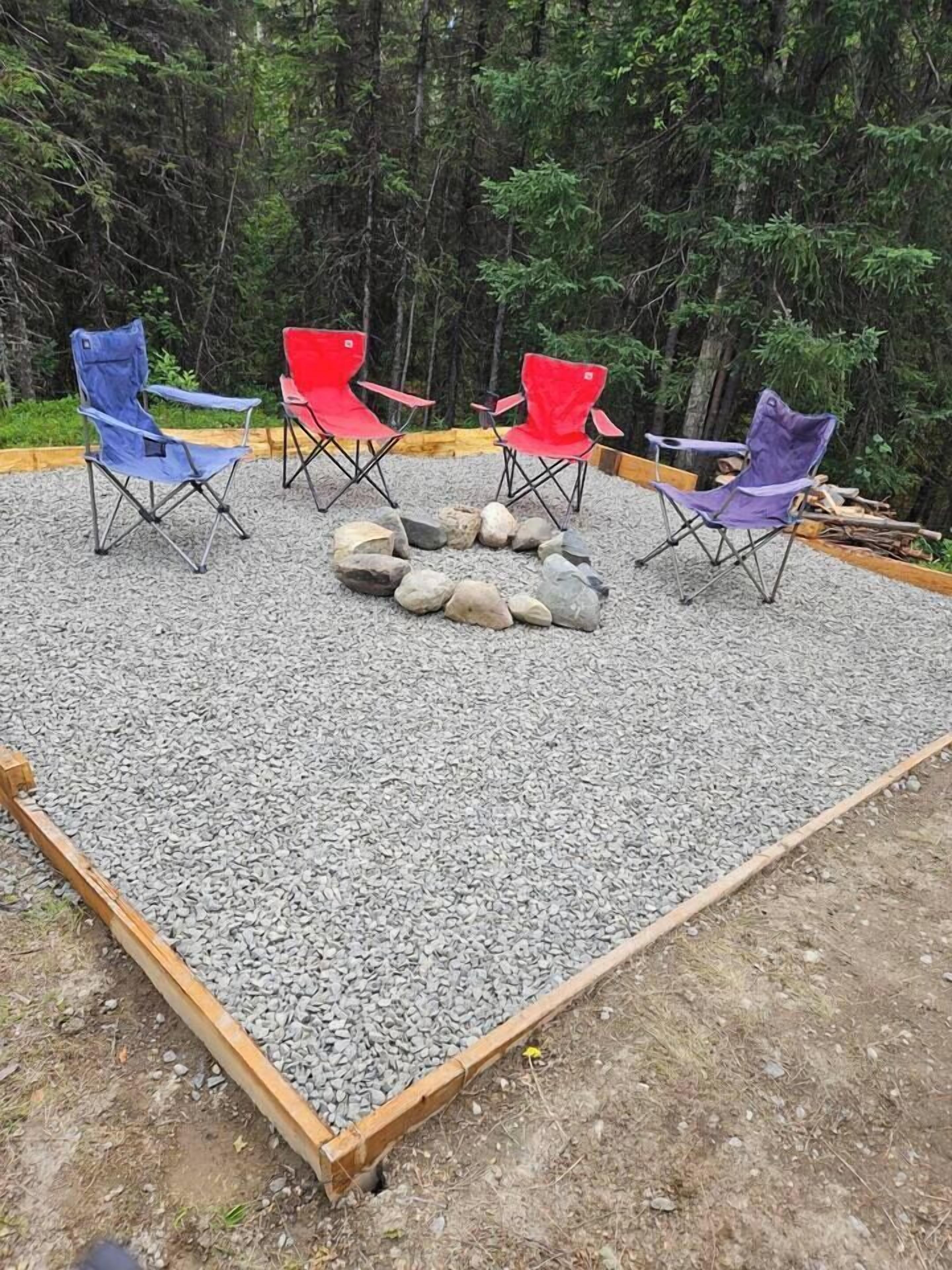 Een terras met vier opklapbare stoelen rond een vuurkuil.