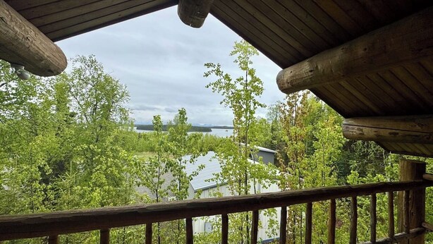 Une terrasse en bois avec une rambarde, donnant sur un lac et des arbres.
