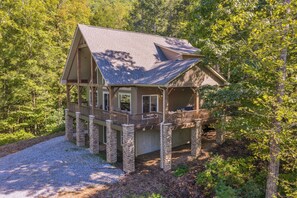 A cabin with a deck, surrounded by trees.