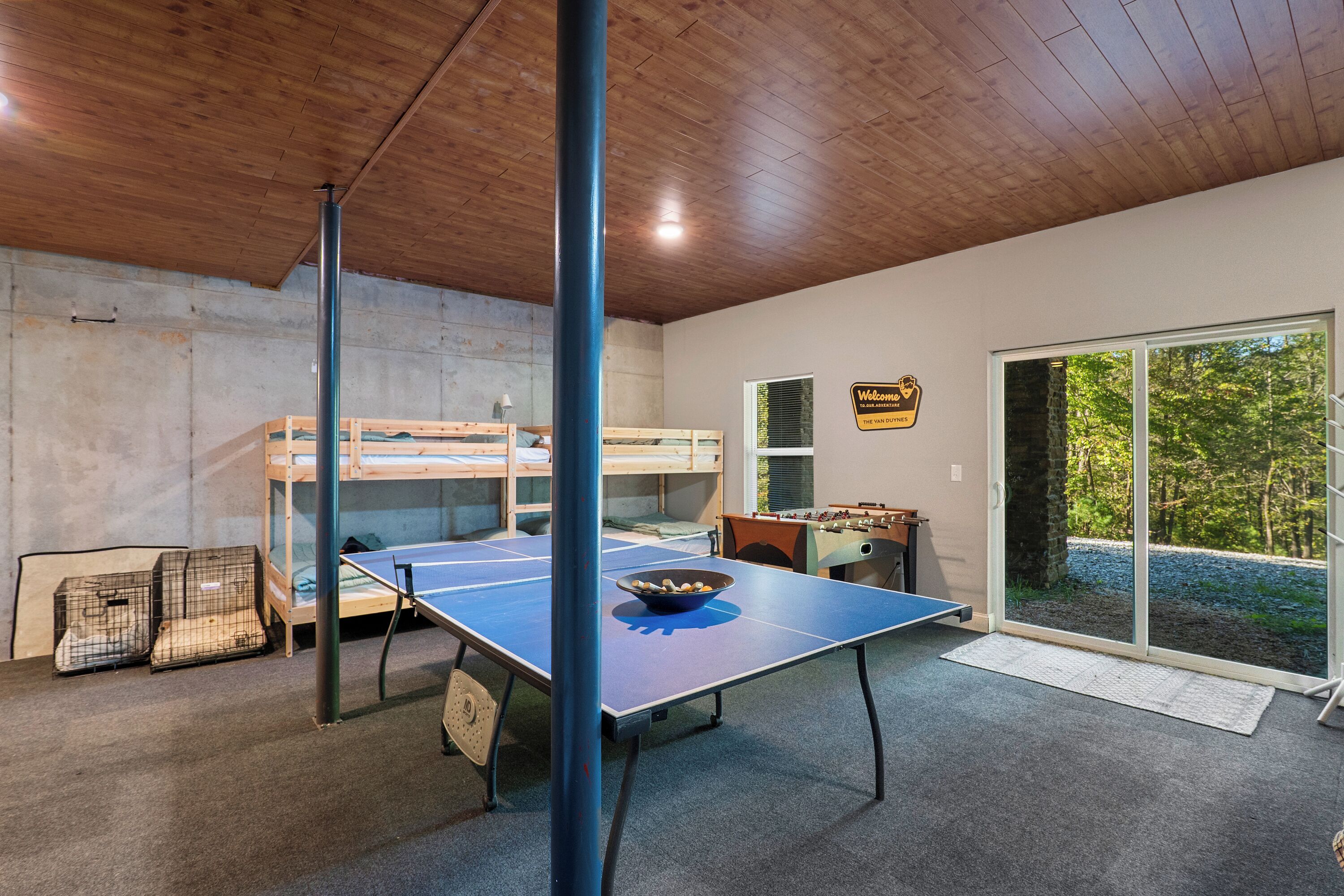 Una habitación con literas, mesa de futbolín y mesa de ping pong.