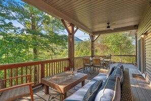A covered outdoor deck with a wooden table, chairs, and a sofa.