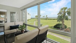 A modern room with large windows, a sofa, a table, and a potted plant. - Luxe Waterfront Condo on Longboat Key - Beach Breeze (Longboat Key)