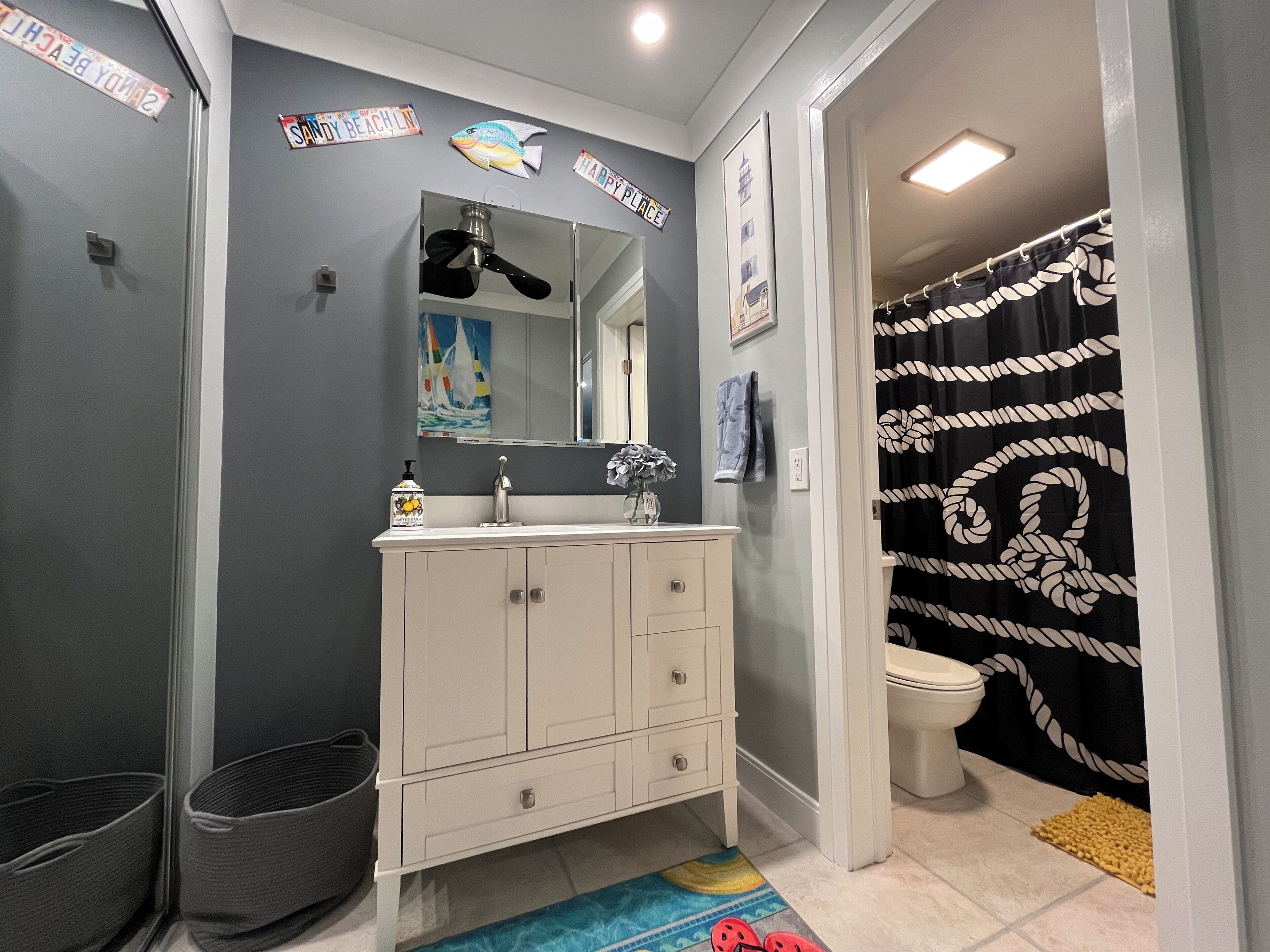 A bathroom with a white vanity, a mirror, a towel rack, and a shower curtain.