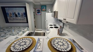 Een compacte keuken met witte kastjes, een fornuis en een spoelbak. Op het aanrecht staan twee borden met een vismotief.