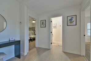 Ein Flur mit einer Rezeption, gerahmten Kunstwerken und einer Tür zu einem Schlafzimmer.
