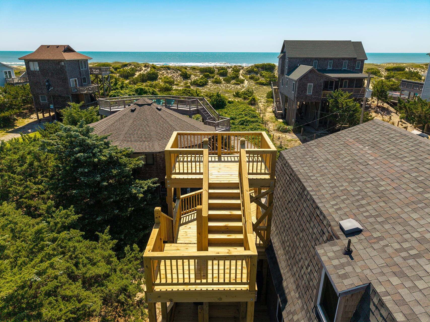 A coastal residential area with multiple houses, a wooden deck, and a view of the ocean.