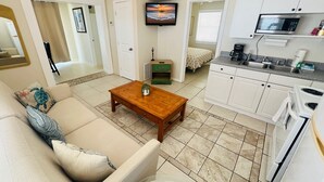 A compact living space with a sofa, coffee table, TV, kitchenette, and a small dining area. - Beach & Relaxation, 2BR, Family + Dog Friendly (Redington Shores)