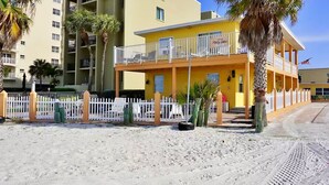 A two-story building with a balcony, a white fence, and palm trees. - Beach & Relaxation, 2BR, Family + Dog Friendly (Redington Shores)
